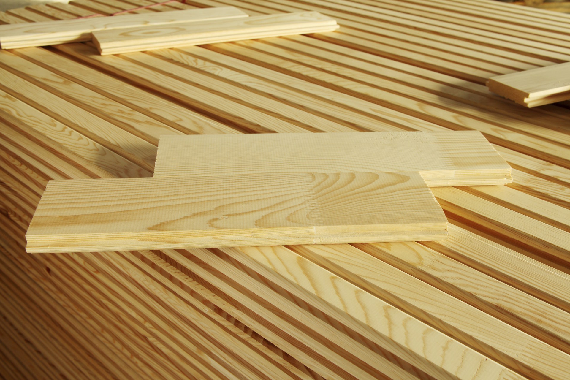 Hobelwaren Die Hobelwaren von HolzPartner in Rathenow sind die perfekte Wahl für Bau- und Ausbauprojekte in Berlin und Brandenburg. Glatt gehobelt, maßhaltig und sofort einsetzbar, bieten sie höchste Qualität für langlebige Konstruktionen. Bildbeschreibung: Gestapelte, hellgelbe gehobelte Holzleisten mit glatter Oberfläche und deutlicher Maserung, teilweise lose aufgelegt.