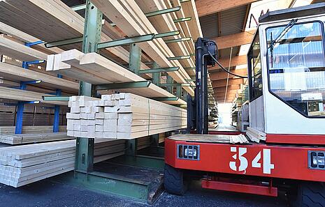Das Konstruktions- und Bauholz von HolzPartner in Rathenow ist perfekt für Bauherren, Handwerker und Heimwerker in Berlin und Brandenburg, die auf Qualität und passgenaue Zuschnitte setzen. Ideal für Dachstühle, Carports oder individuelle Holzprojekte.  Bildbeschreibung: Lagerhalle mit Bauholzstapeln in verschiedenen Größen, ein Gabelstapler steht daneben zum Transport der Holzbalken.
