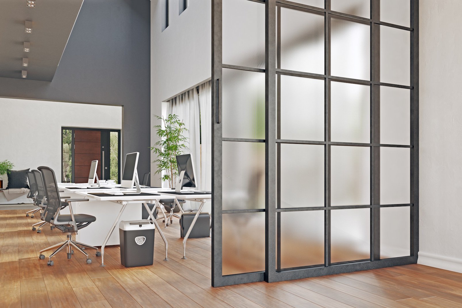 Raumteiler Die Raumteiler von HolzPartner in Rathenow bieten flexible Gestaltungsmöglichkeiten für Wohnungen und Büros in Berlin und Brandenburg. Sie schaffen Struktur, ohne Licht zu nehmen, und verbinden elegantes Design mit praktischer Raumaufteilung. Bildbeschreibung: Moderner Raumteiler aus Glas mit schwarzem Metallrahmen in einem großzügigen Büro mit Holzfußboden und Schreibtischen.
